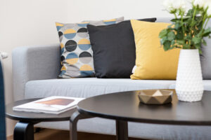 Grey couch with three large throw pillows on it